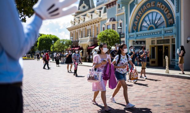 A cast member (L) welcomes visitors upon their arrival at Hong Kong's Disneyland on June 18, 2020, ...