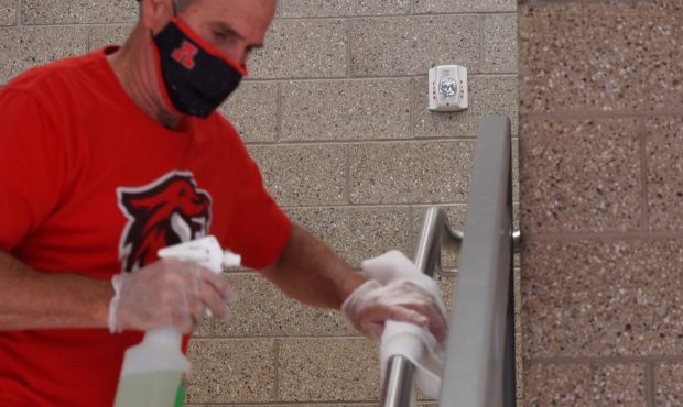 A custodian sanitizes hand rails at American Fork High School....