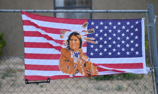 FILE: An American flag with an image of Native American on it is attached to a fence outside a home...