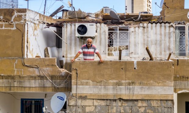 A man poses for a photograph on the balcony of his damaged home on August 12, 2020 in Beirut, Leban...