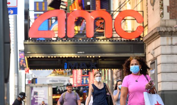 People wear protective face masks outside the AMC Empire 25 movie theater in Times Square as the ci...
