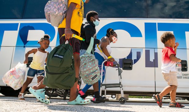 A family walks to a charter bus that will evacuate them from Galveston Island to Austin in anticipa...