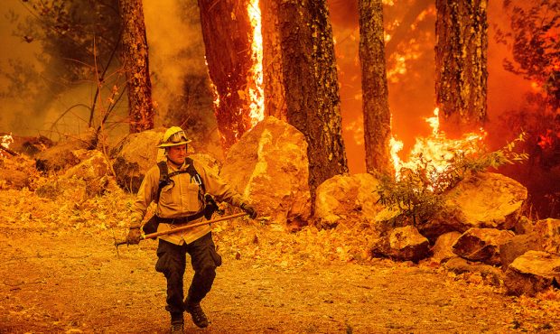 A firefighter walks a path as the Glass Fire burns along Highway 29 in Calistoga, Calif., on Thursd...