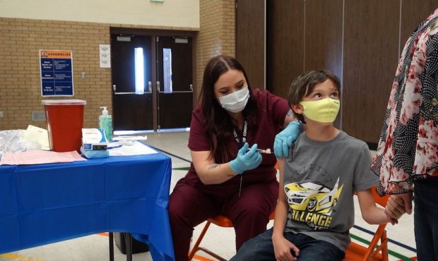 Ten-year-old Xander Wilde holds his mom's hand while getting his flu shot at Bennion Elementary Sch...