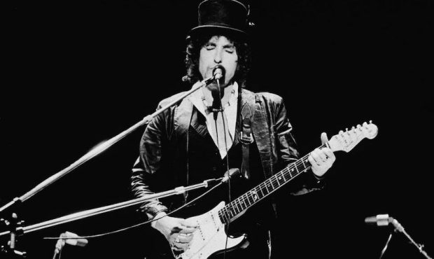 FILE: American singer and songwriter Bob Dylan sings and plays guitar on stage, wearing a top hat, ...