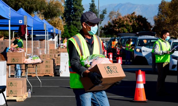 Food is loaded as drivers in their vehicles wait in line on arrival at a "Let's Feed LA County" foo...