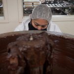 An employee works in front of a vat of chocolate.
