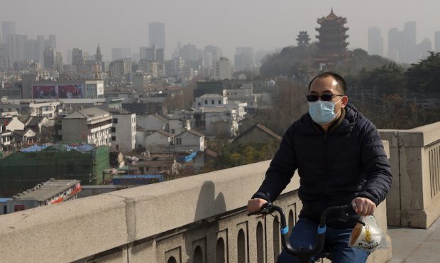 A Chinese man wearing face mask as riding an electric bike to cross the Yangtze River on January 28...