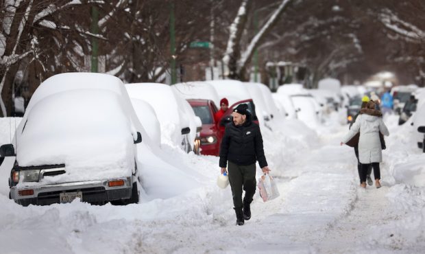 People navigate a snow-covered street on February 16, 2021 in Chicago, Illinois. Chicago residents ...