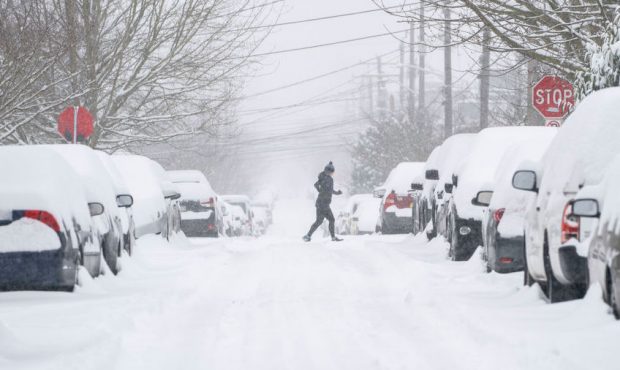 A jogger makes their way across a snowy street on February 13, 2021 in Seattle, Washington. A large...