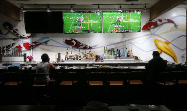 Restaurant workers sit during a break as Super Bowl LV plays on televisions in the shuttered indoor...