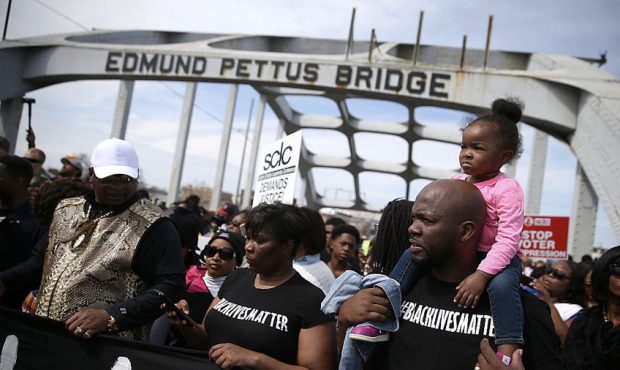 People pause for prayer as they walk across the Edmund Pettus Bridge during the 50th anniversary co...
