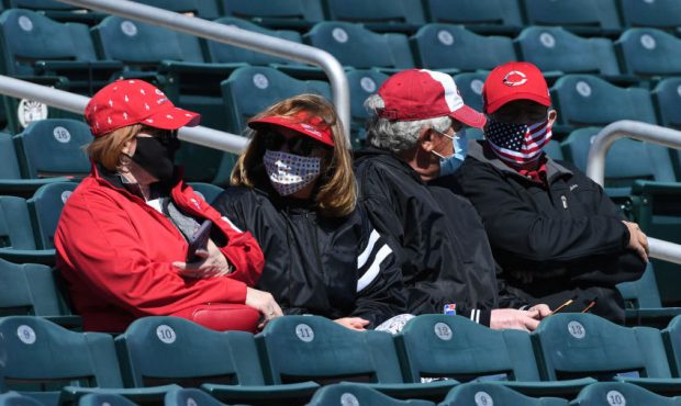 Cincinnati Reds fans wearing masks sit in the stands prior to a spring training game between the Cl...