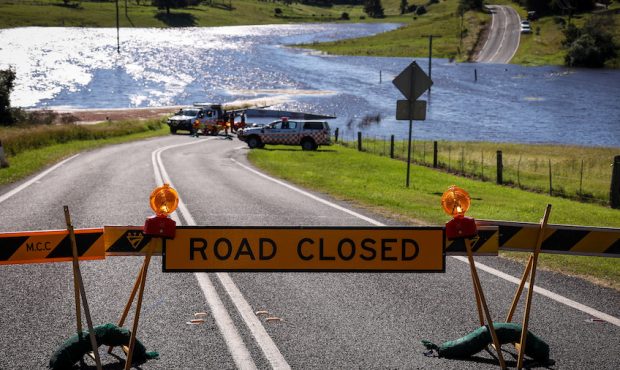 Members of the NSW State Emergency Service wait to transport locals in a boat across a road that is...
