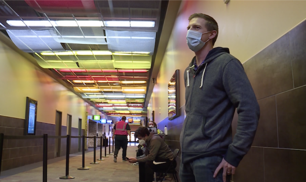 Dustin Bunderson waits at a Megaplex Theatre location, hoping to get a leftover COVID-19 vaccine do...