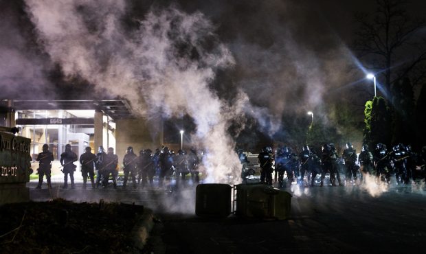 Tear gas fills the air as people confront police outside the Brooklyn Center police headquarters on...