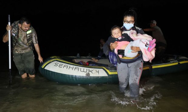 A migrant from Guatemala holding a child arrives in the U.S., crossing the Rio Grande in a raft pil...