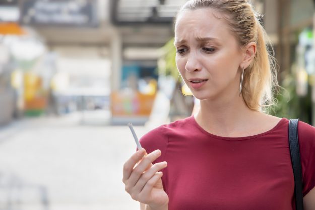 woman in red shirt holds cigarette with distressing expression