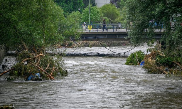 A man crosses a bridge over the Volme River near debris caused by flooding on July 16, 2021 in Hage...
