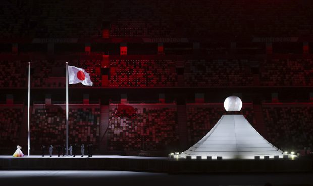 The Olympic Cauldron is seen as the Japanese Flag is raised during the National Anthem during the O...