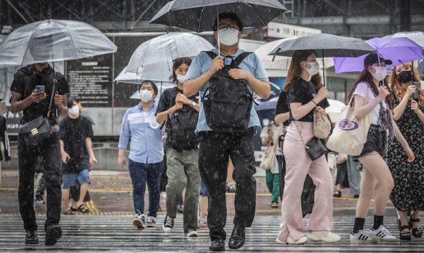 People cross Shibuya crossing in heavy rain on July 30, 2021 in Tokyo, Japan. Japan’s Prime Minis...