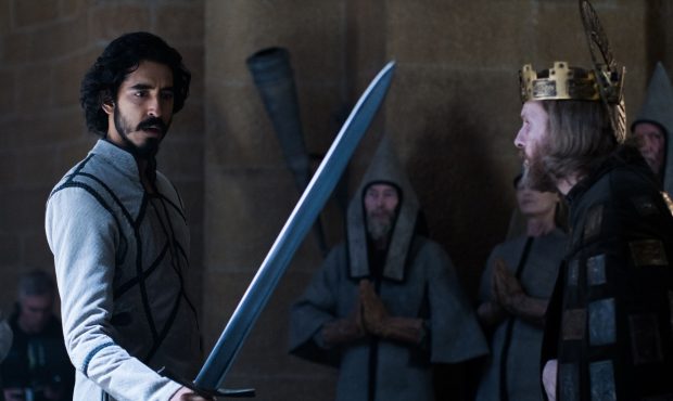 Gawain (Dev Patel) holds the King's (Sean Harris) sword in A24 Films' THE GREEN KNIGHT....