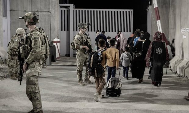 U.S. Army soldiers with the 82nd Airborne escort evacuees to buses at Hamid Karzai International Ai...