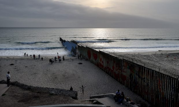 The sun begins to set beyond the U.S.-Mexico border barrier running into the Pacific ocean on July ...