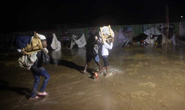 People leave as Tropical Storm Grace hits a refugee camp at a football field called Parc Lande de G...