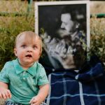 One-year-old Greyson Mair poses in front of a picture of his late father, Jordan Mair, holding him as a newborn. Just two months after Greyson was born, Jordan died by suicide. (Summer Smart/KeniB Photography)