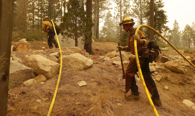 Cal Fire firefighters pull a hose while battling the Caldor Fire on August 31, 2021 in Meyers, Cali...