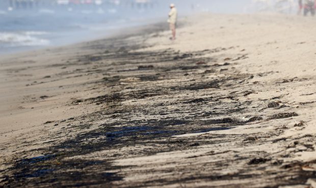 A person stands near oil washed up on Huntington State Beach after a 126,000-gallon oil spill from ...