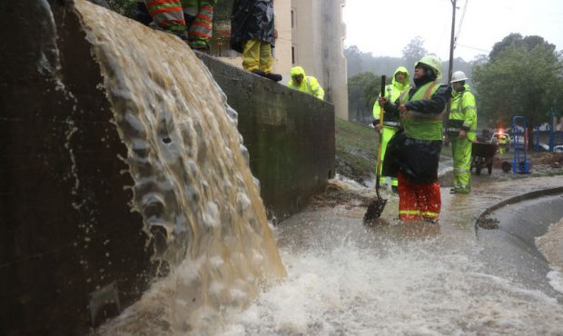 Workers try to divert water into drains as rain pours down on October 24, 2021 in Marin City, Calif...