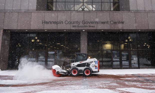 Crews work to clean snow off the walkway outside the Hennepin County Government Center on December ...