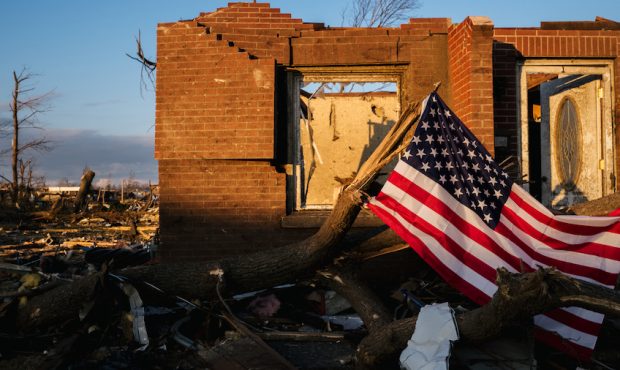 An American flag is seen in front of a damaged home at sunrise on December 14, 2021 in Mayfield, Ke...