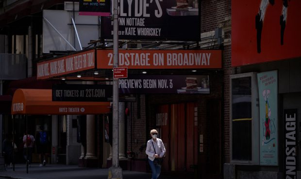A pedestrian wearing a mask stands walks past a Broadway theatre in New York city on July 30, 2021....