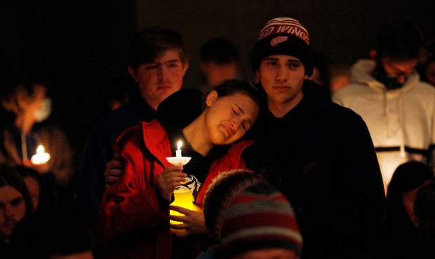 A person becomes emotional as students holding candles are asked to stand during a vigil after a sh...