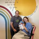 Bethany and Scott England pose in front of a mural while holding baby Piper at Intermountain Logan Regional Hospital. (Intermountain Healthcare)