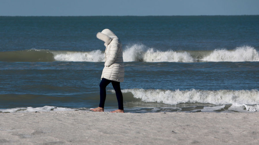 Michelle Foster, from Oklahoma, bundles up against the cool weather while strolling along the beach...
