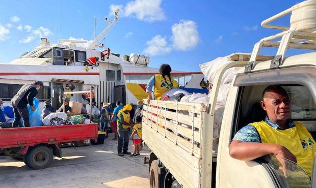 Trucks containing donated supplies from church members are loaded onto a boat bound for the outer i...