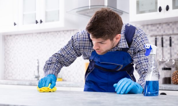 Close-up Of A Young Man Cleaning Dirty Kitchen Counter With Napkin...