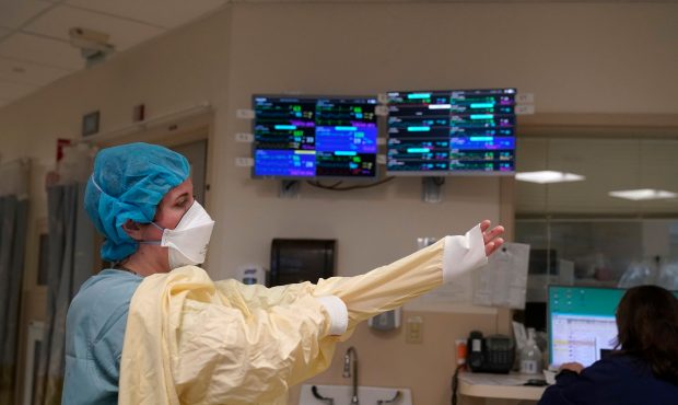 FILE - A nurse suits up with protective gear before entering a patient's room at the COVID-19 Inten...