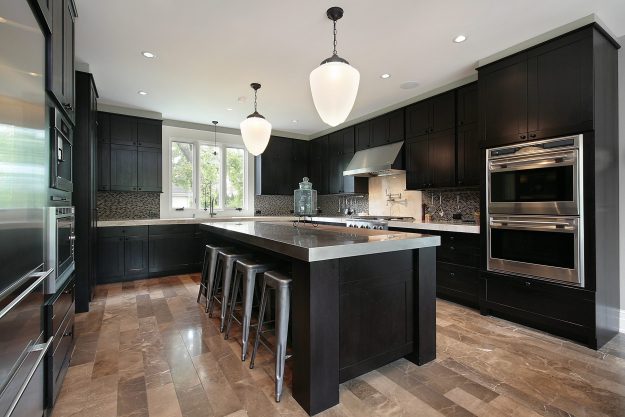 kitchen with black metal cabinets and stainless steel island, with 2 hanging lamps above