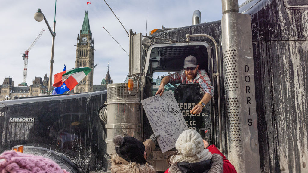 OTTAWA, ON - JANUARY 30: Trucker signs a protestors sign during a rally against COVID-19 on Parliam...