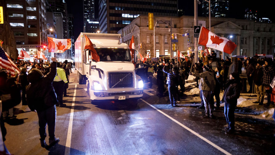 Supporters wave flags as a convoy of trucks leave from Bloor St. and University Ave. on February 5,...