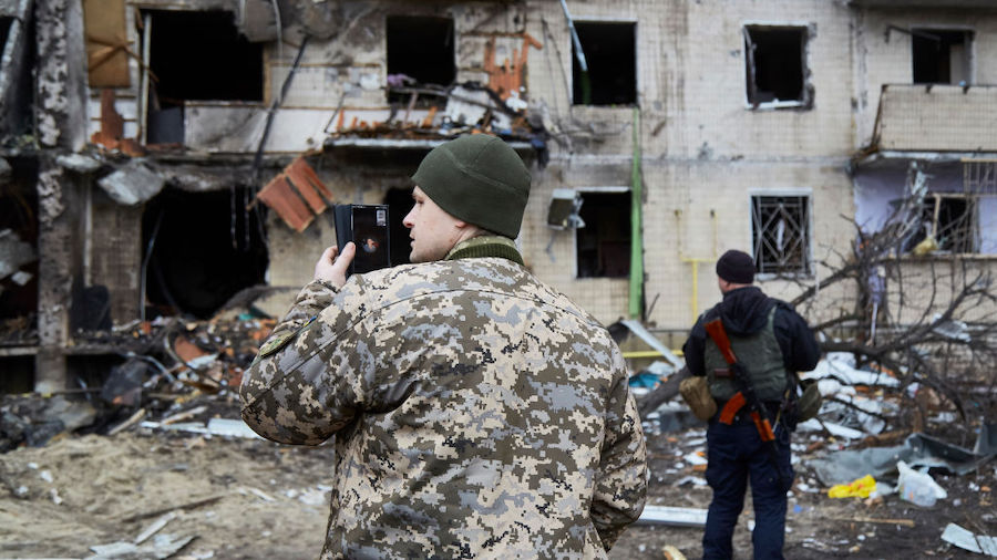 A Ukrainian soldier speaks on his smartphone outside a residential building damaged by a missile on...