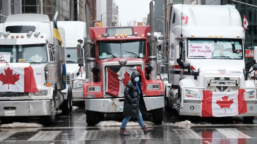 People walk near Canadian Parliament buildings as hundreds of truck drivers and their supporters ga...