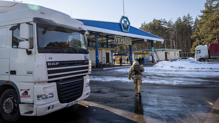 A member of the Ukrainian Border Guard walks between trucks waiting to cross the border at the Thre...