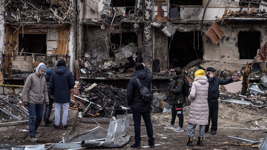 People look at the exterior of a damaged residential block hit by an early morning missile strike o...