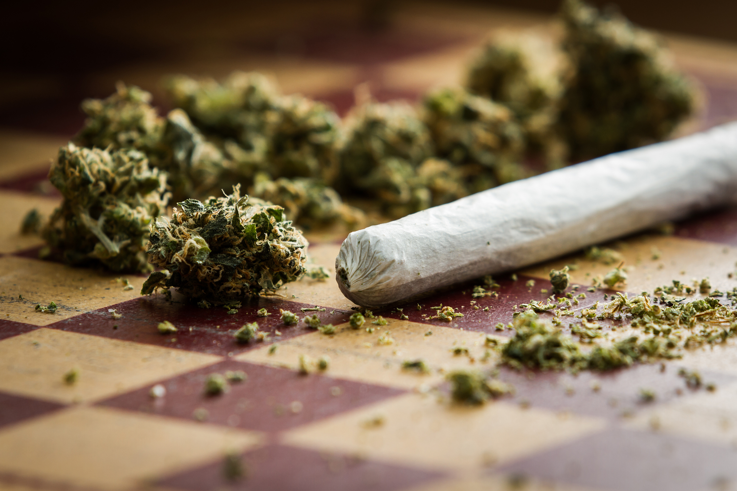 closeup of marijuana joint and buds on a checkerboard table with a shallow depth of field...